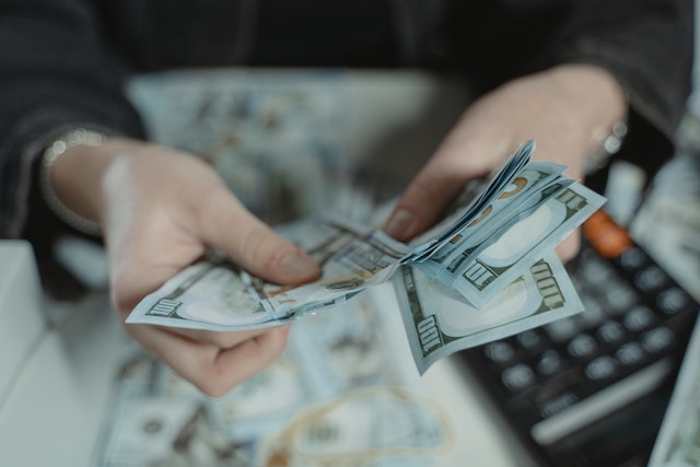 person holding a bunch of cash with a calculator next to them